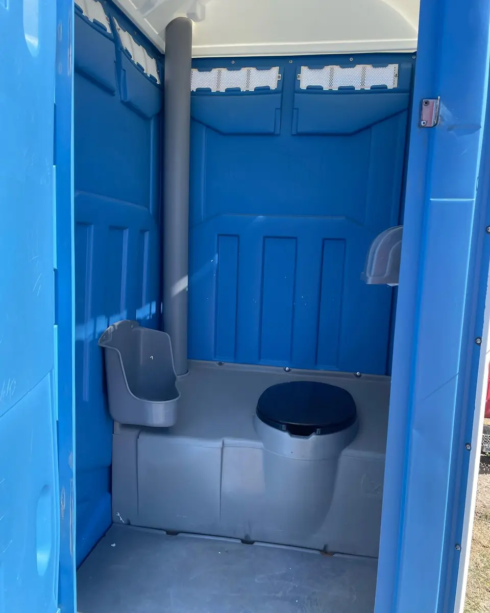 Inside a standard porta potty: seat, urinal and tissue holders.