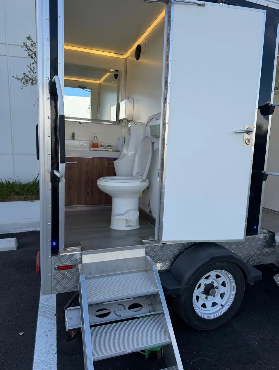 Porcelain toilet and wood vanity in a trailer stall.