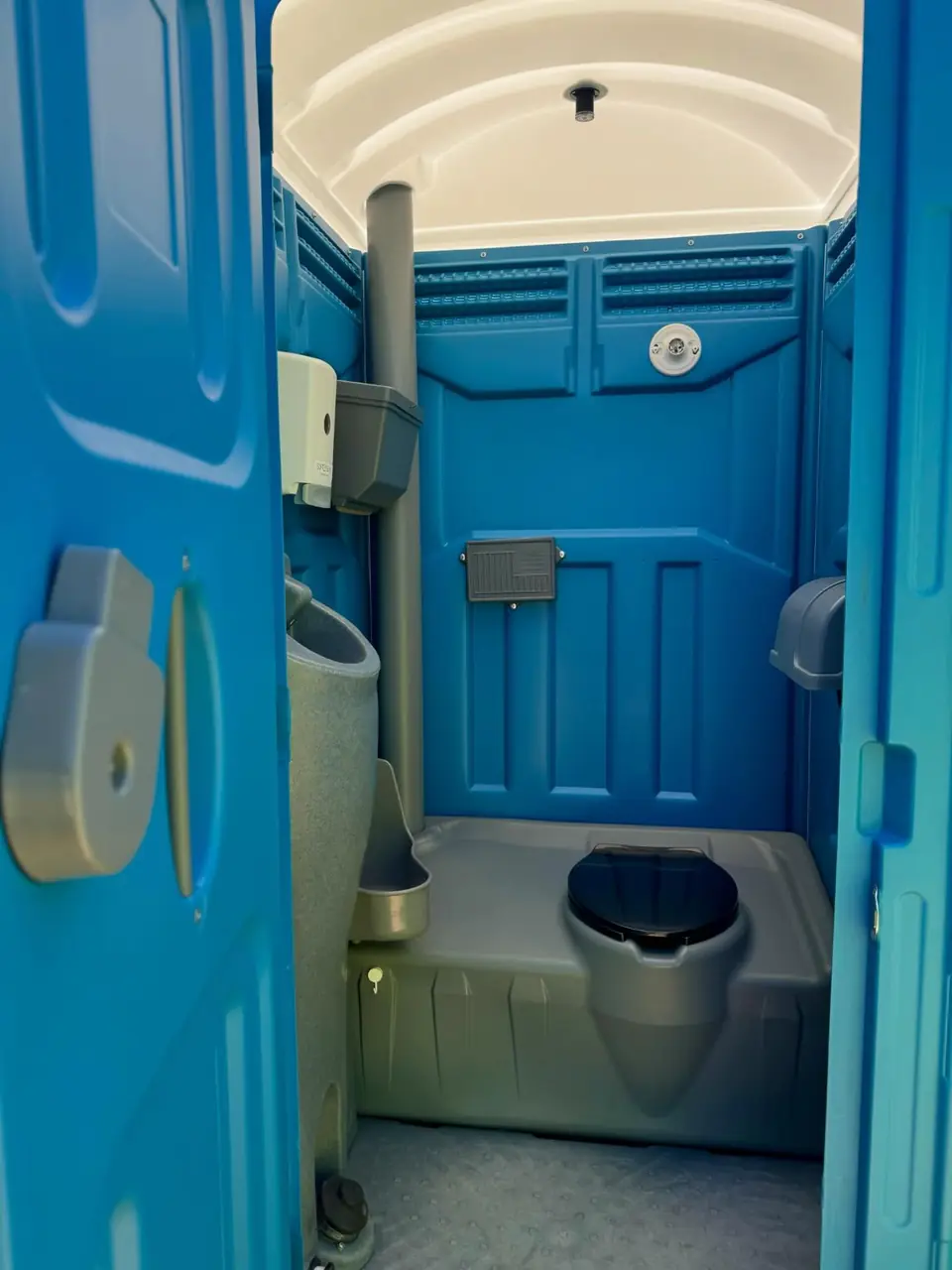 Inside a standard porta potty: seat, urinal and tissue holders.