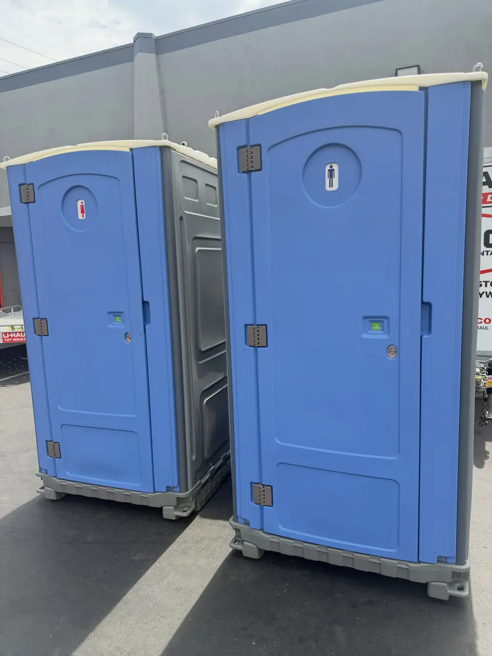Two blue portable toilets parked side by side on pavement