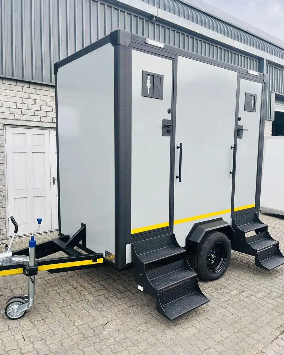 A two-stall restroom trailer with steps and a hitch.