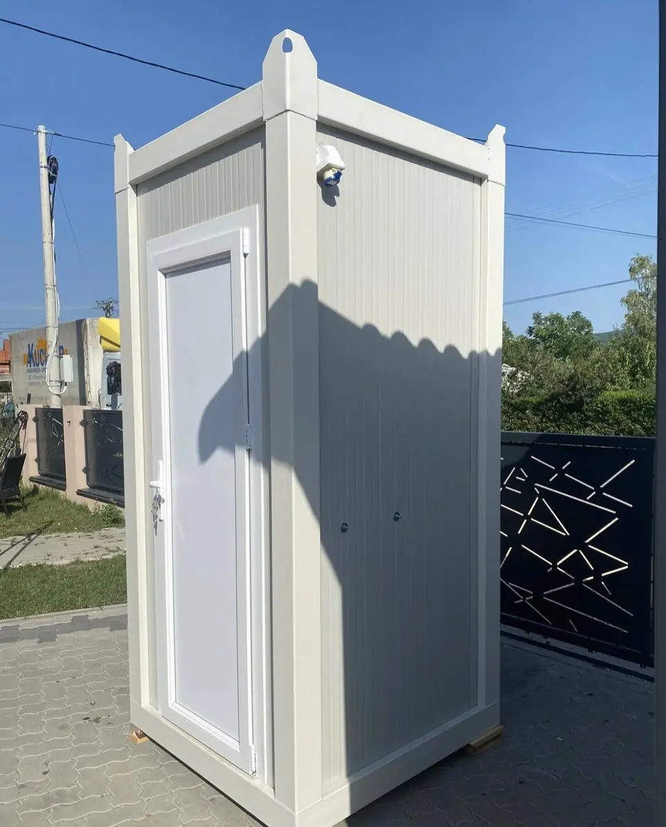 White flushing restroom cabin beside a gate
